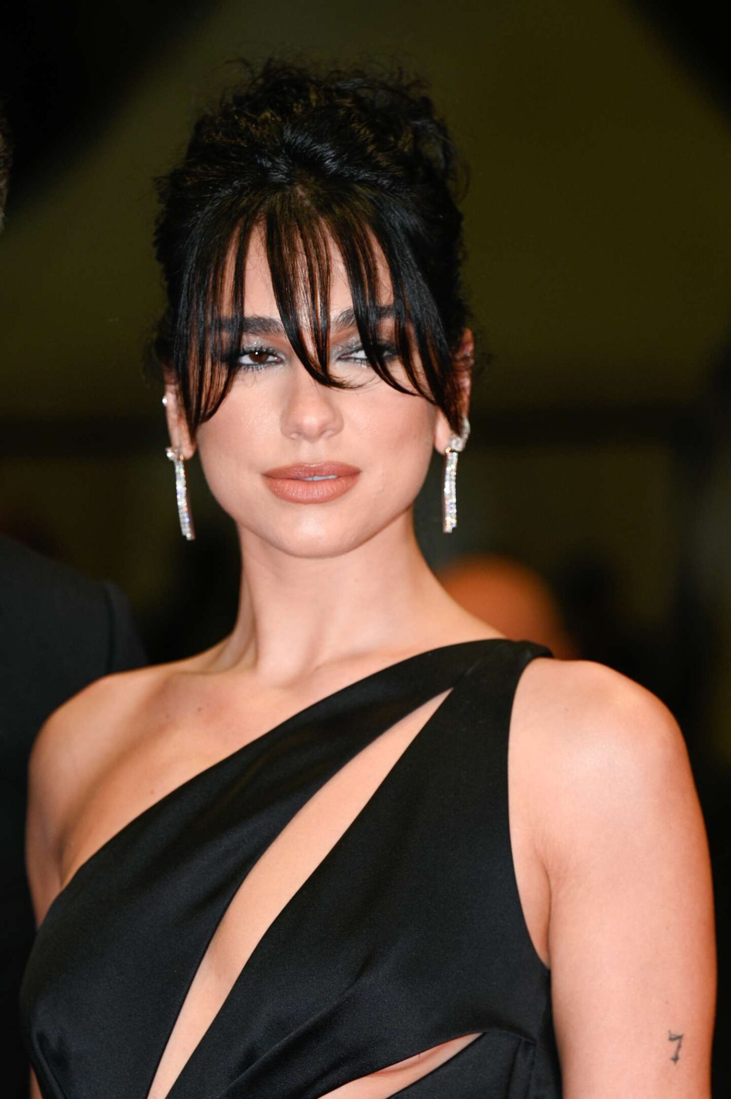 Sleek updo with long separated wispy bangs and statement face framing